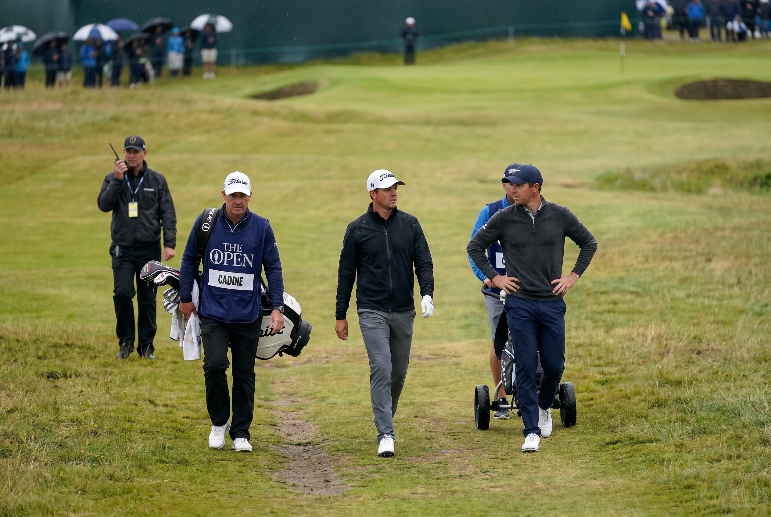 Editorial golf image of players and a caddie walking between shots during a professional round.