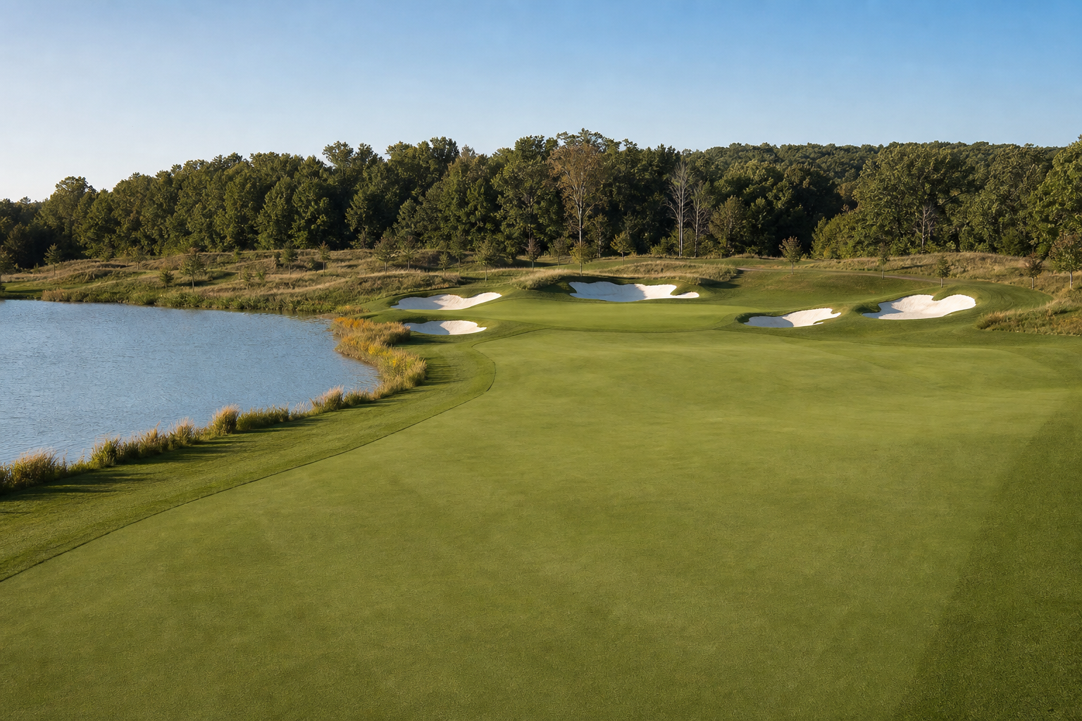 Open golf hole with water and bunkers framing a fairway landing area